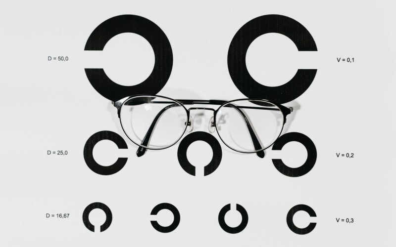 A close-up view of eyeglasses placed on a Snellen chart used for vision testing.
