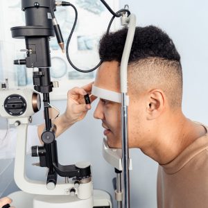 A young man undergoes an eye examination using a slit lamp in a medical clinic.